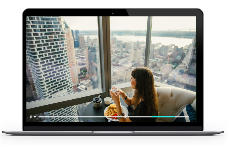 Vidéo présentant une femme admirant un paysage urbain dans un appartement, diffusée sur un ordinateur portable