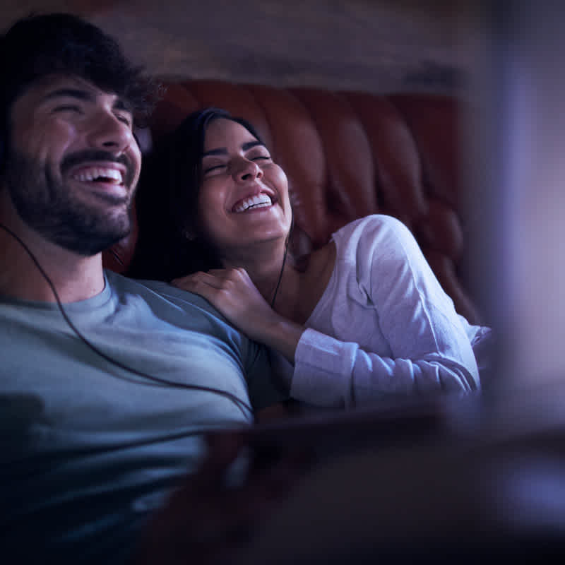 A couple is watching a video and laughing.