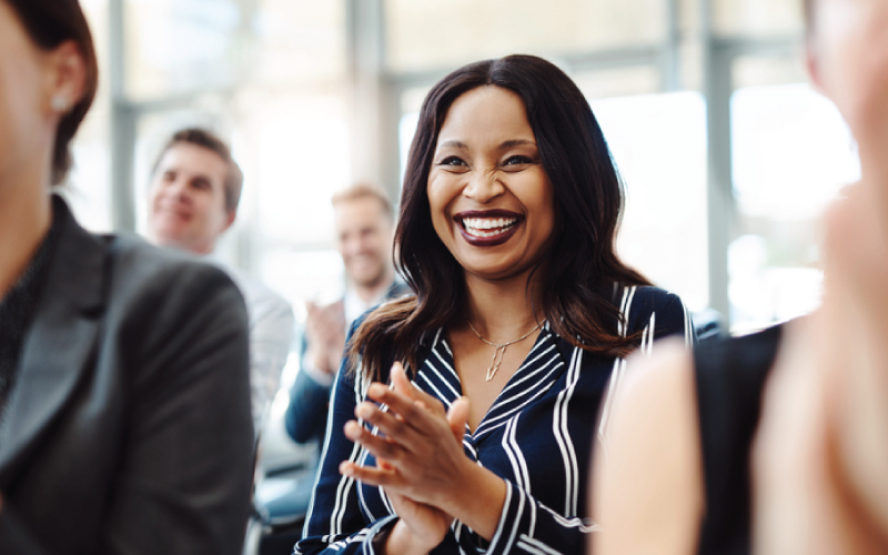 Employees are applauding a presenter in a leadership meeting