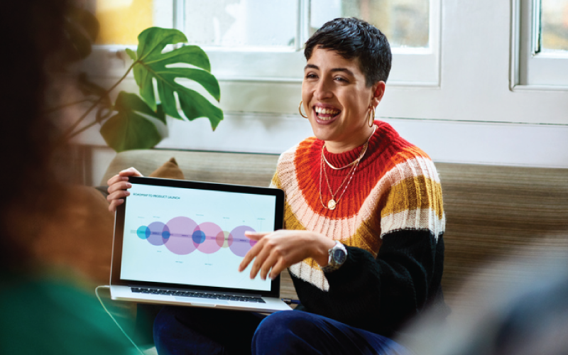 A female employee is presenting project data analytics information to colleagues in a meeting