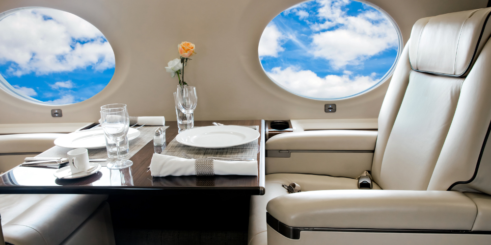 Luxurious dining setup with elegant tableware and a rose by the window inside a private jet tour.