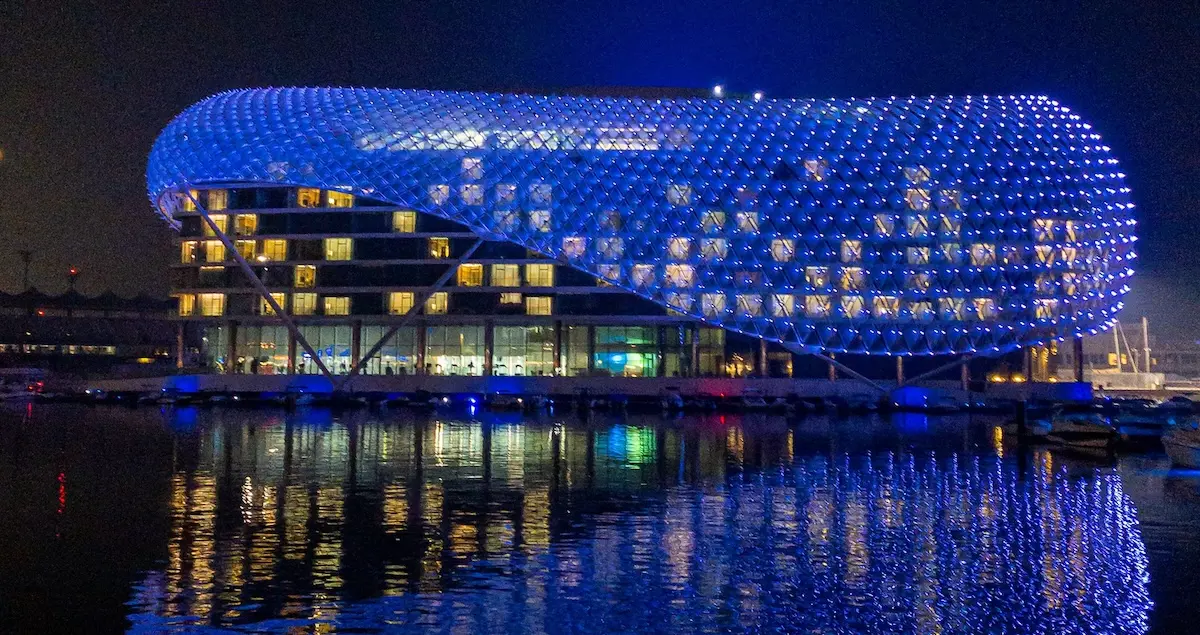 W Hotel situated on Yas Island in Abu Dhabi as seen from the water at night and lit in blue.