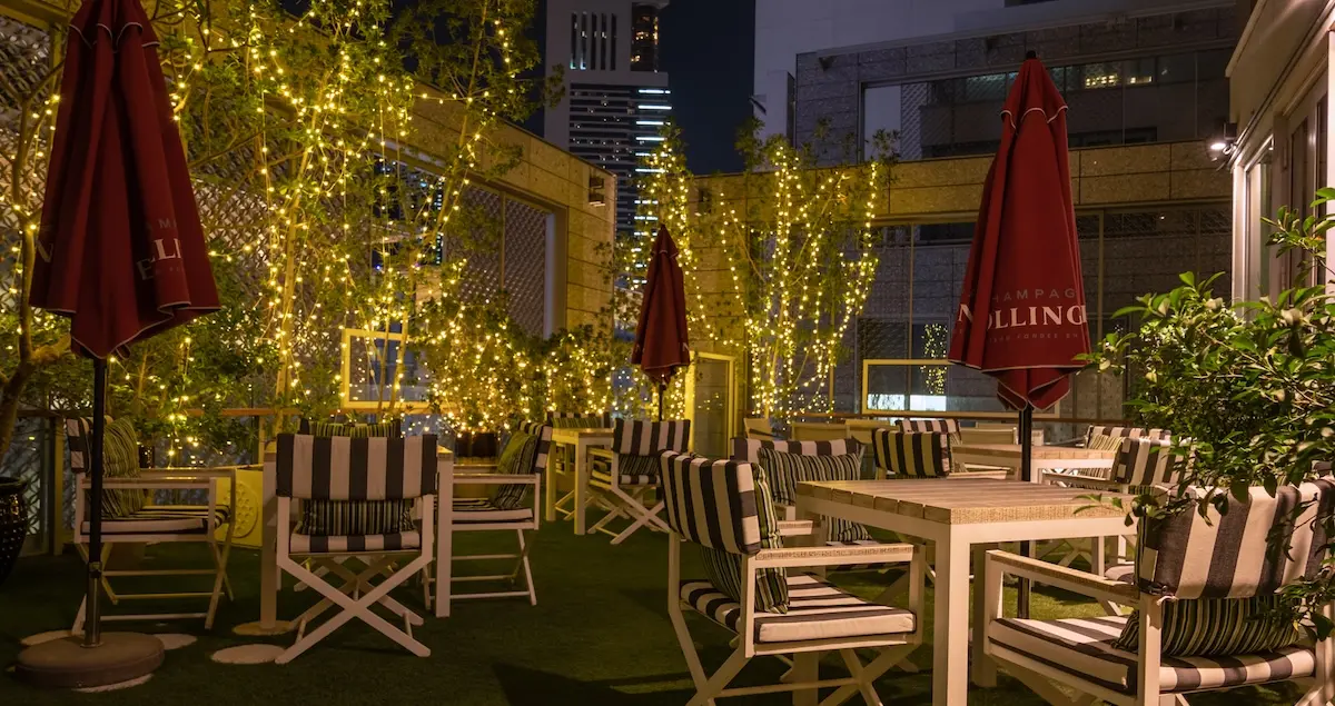 Nightime shot of The Lookout rooftop terrace at The Capital Club in Dubai, showing tables chairs and fairy lights.