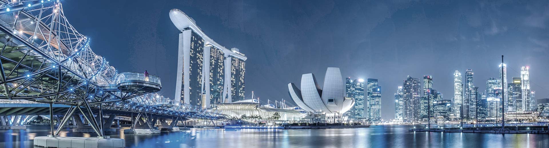La metrópolis moderna de Singapur por la noche, con enormes rascacielos y puentes que iluminan el cielo.