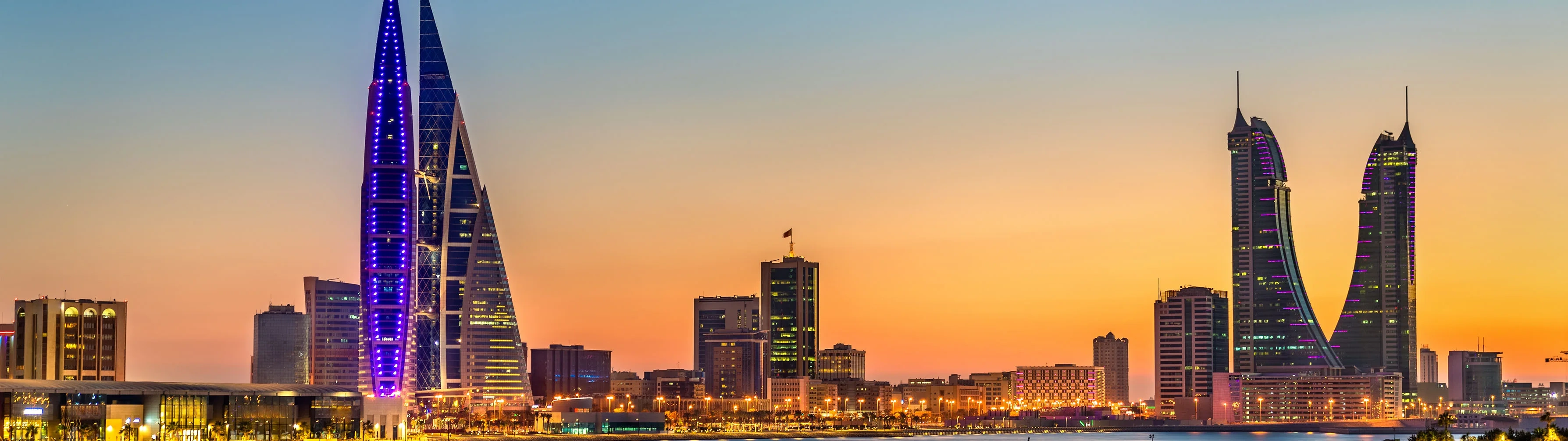 The skyline of the city of Manama in Bahrain, lit up by the sunset.