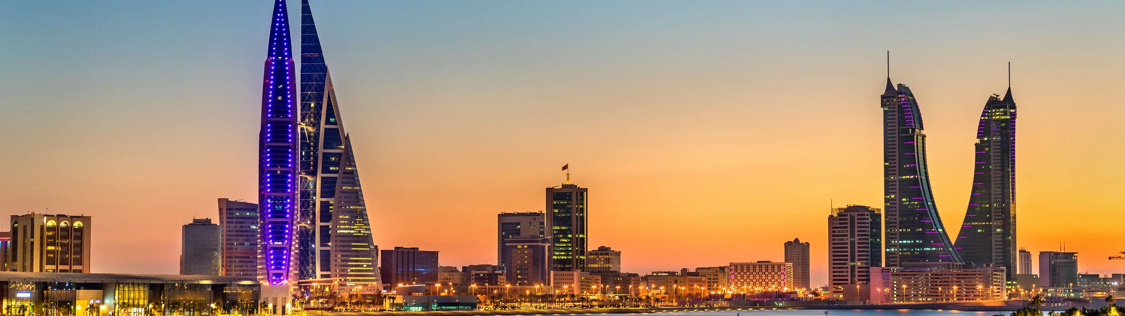 The skyline of the city of Manama in Bahrain, lit up by the sunset.