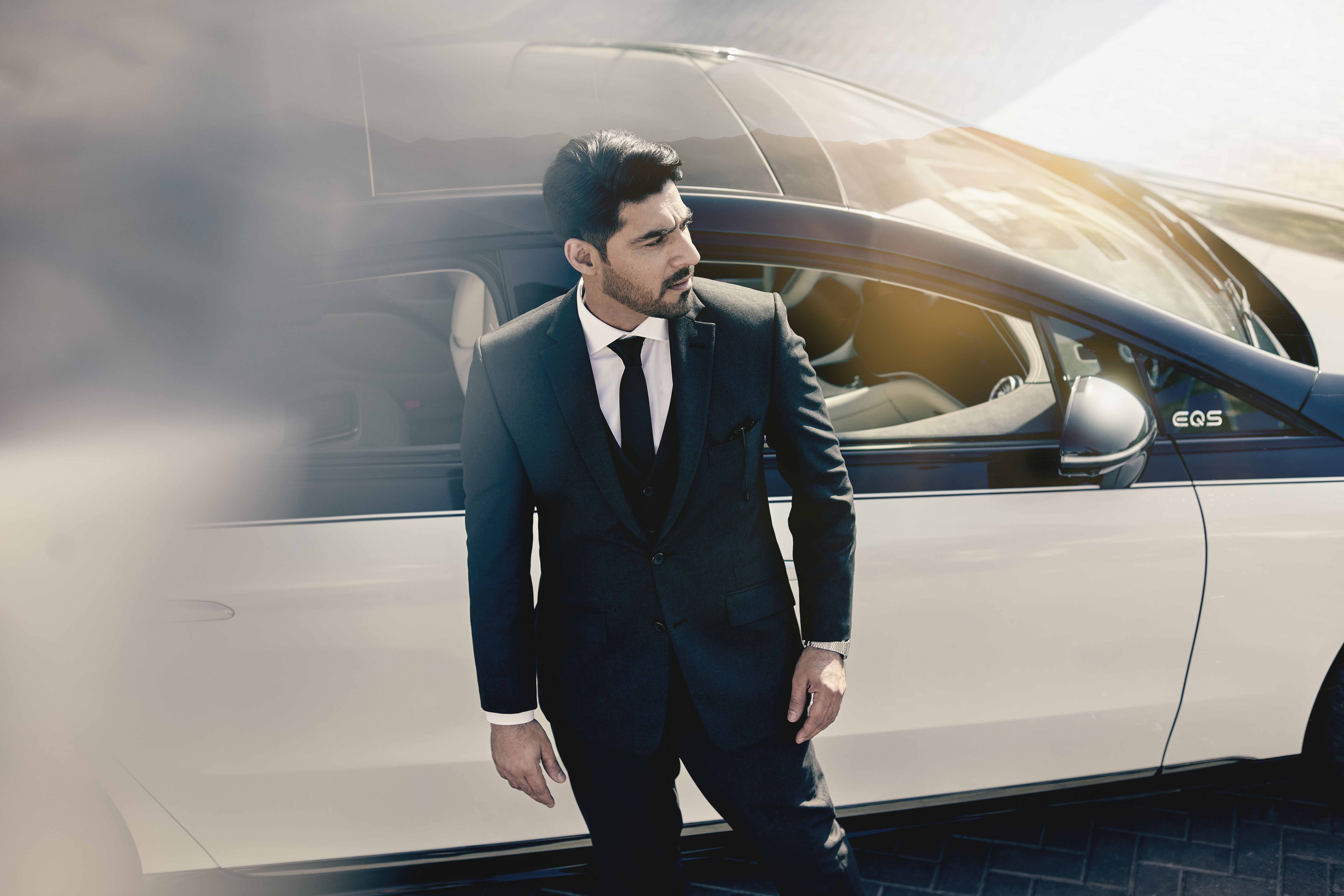 Smartly dressed chauffeur stands near vehicle in Dubai.
