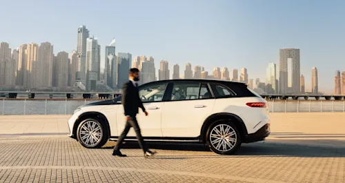 Chauffeur walking to back of two-tone SUV in Dubai