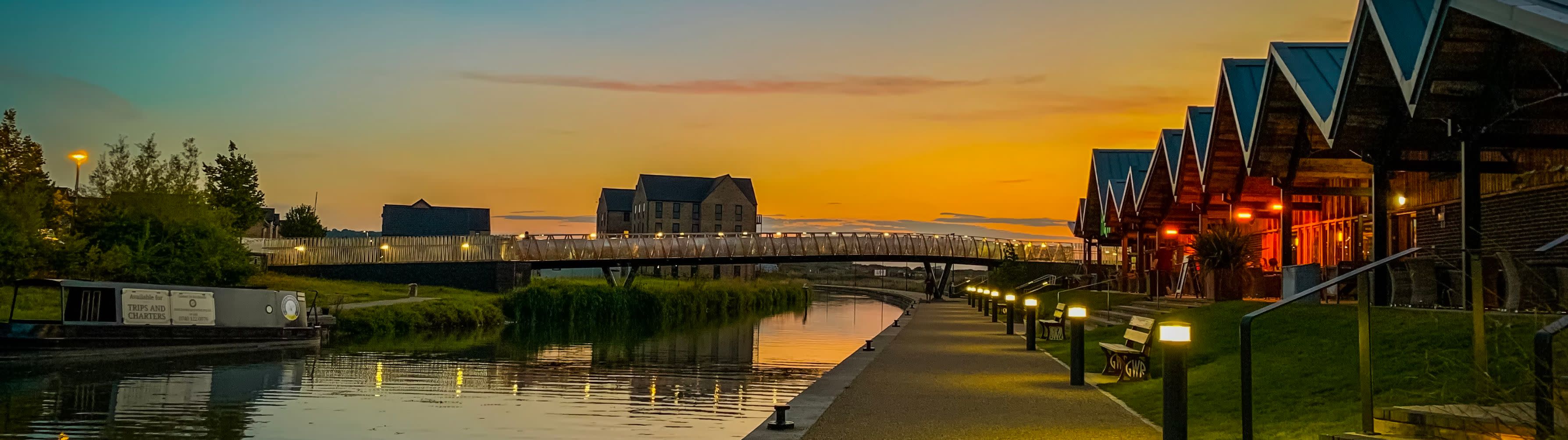 A waterway in Swindon lit up by the light sof nearby houses at dusk or dawn.