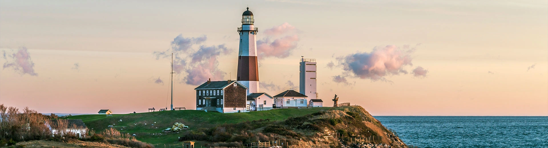 A charming red and white lighthouse stands on the Montauk coastline overlooking the water.