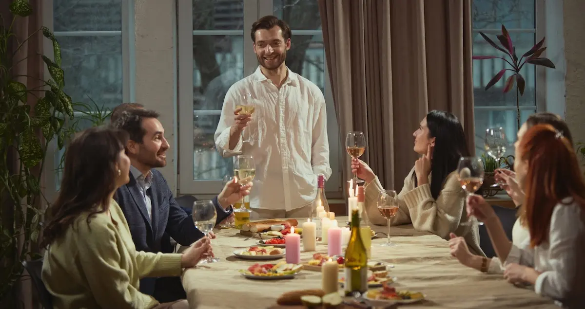 A man standing and making a toast to a small group at a private dining resturant.