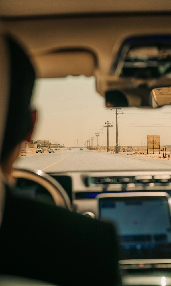Shot over a chauffeur's shoulder at a desert road ahead.