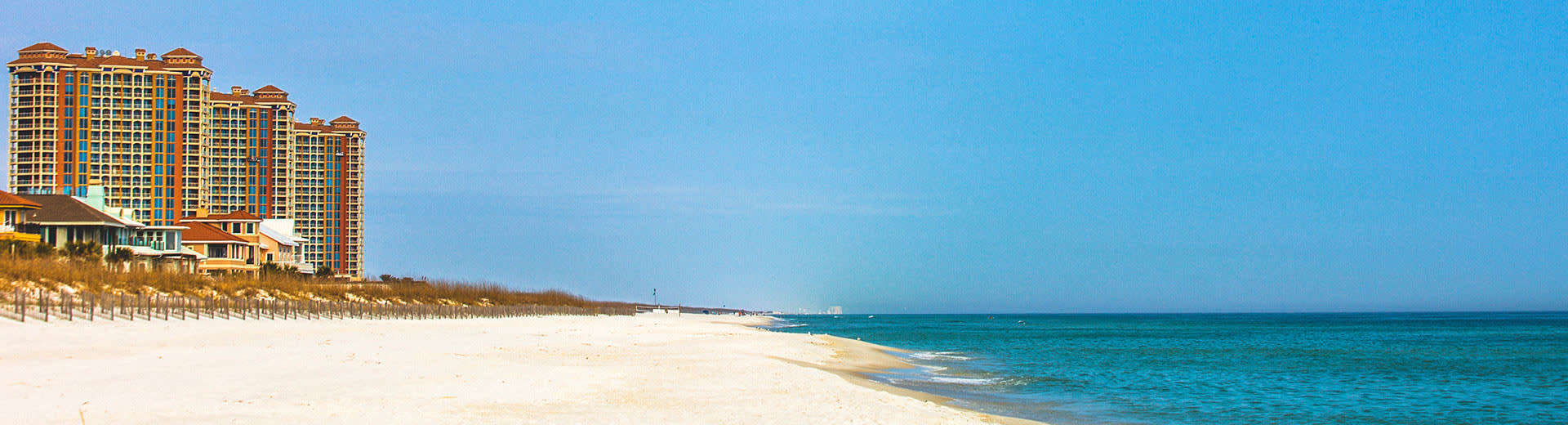 Un hotel frente al mar en la playa de Pensacola mira sobre arena blanca y aguas azules.