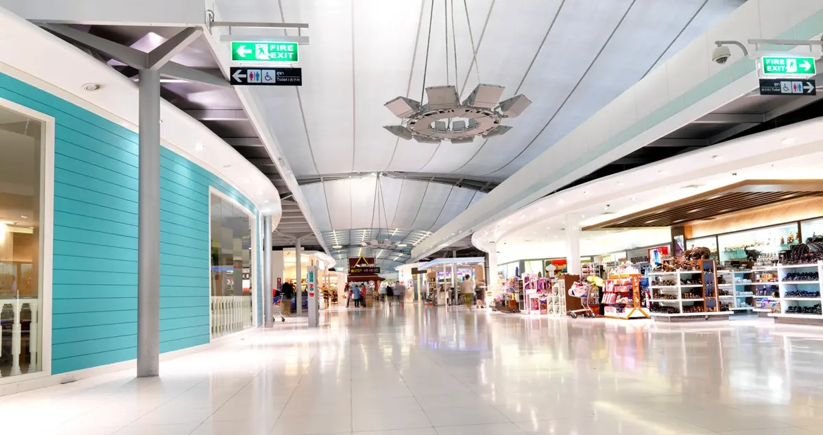 Interior shot of the Duty-Free shopping area of Bangkok Suvarnabhumi Airport, showing bright spaces and empty shops.