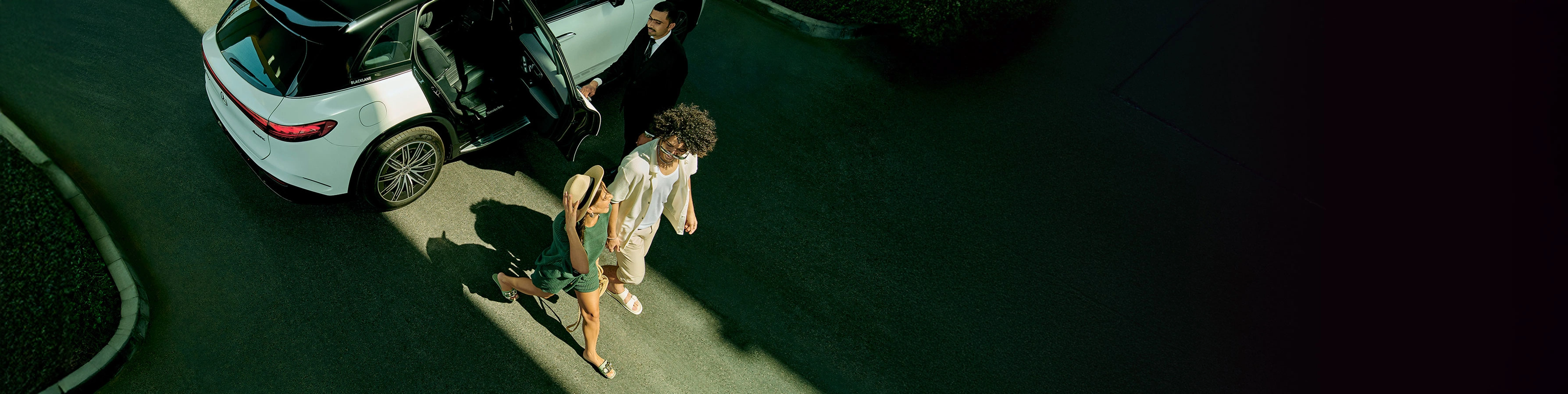 A young couple walks out of a black and white Mercedes-Benz EQS.