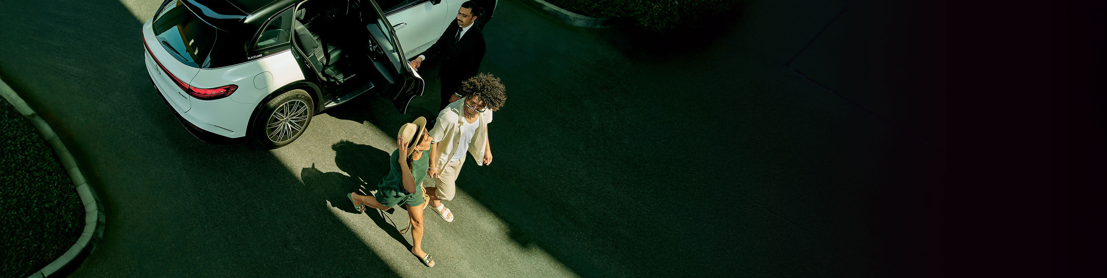 A young couple walks out of a black and white Mercedes-Benz EQS.