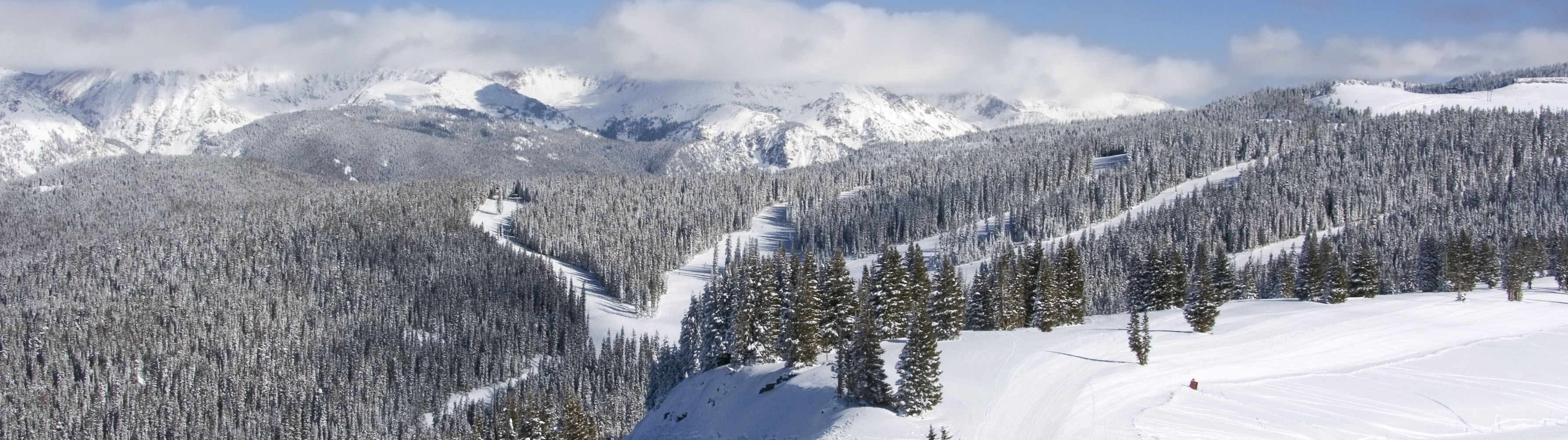 The rolling, snow-packed mountains of Vail on a clear day.
