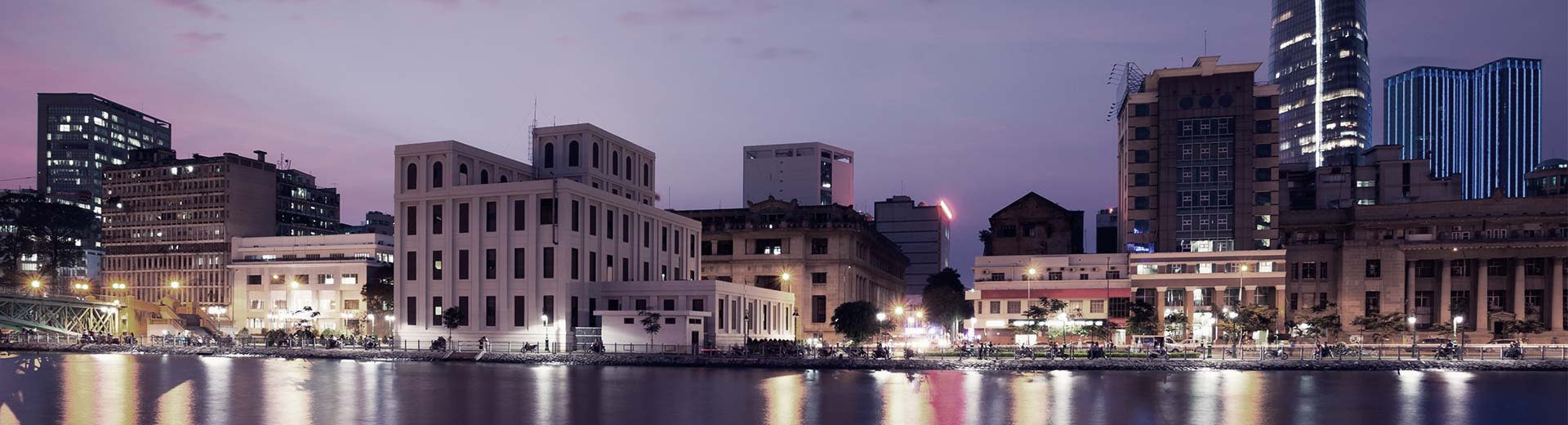 A waterfront vision of Ho Chi Minh City during the low light of either dusk or dawn.