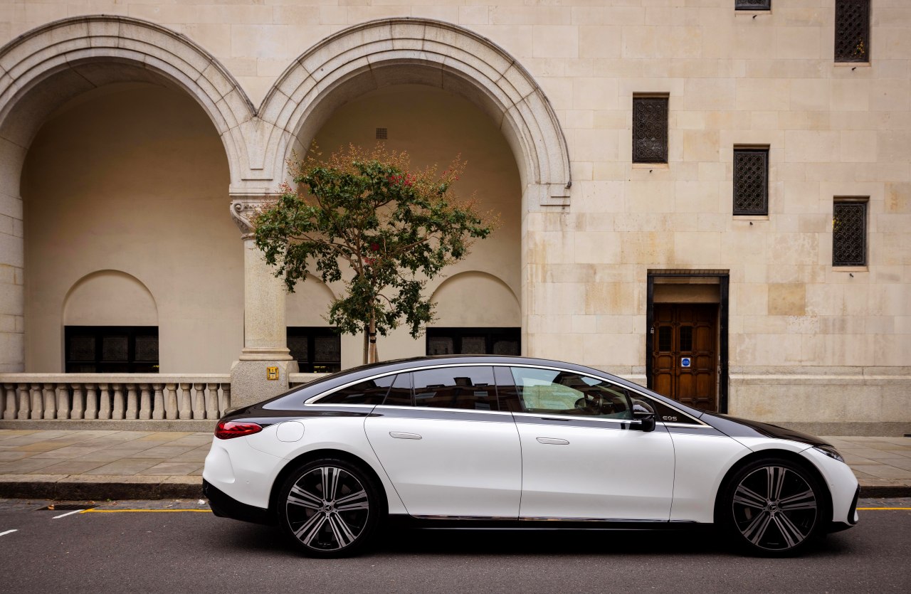 Side shot of a Blacklane two-tone Mercedes EQE limo outside an ornate building.