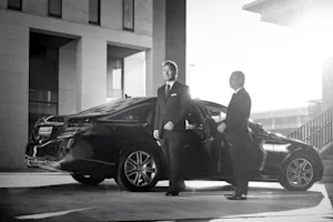 Real Blacklane chauffeur Ben holds the door open for his guest as they exit his Mercedes.