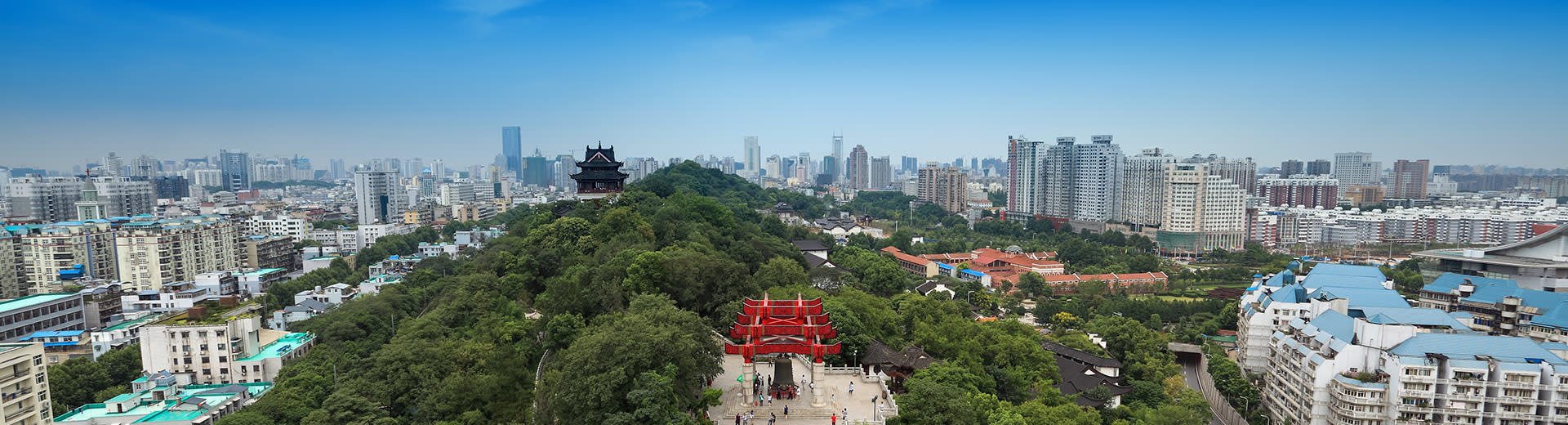 Cielos azules sobre un parque verde y la extensa ciudad de Wuhan.