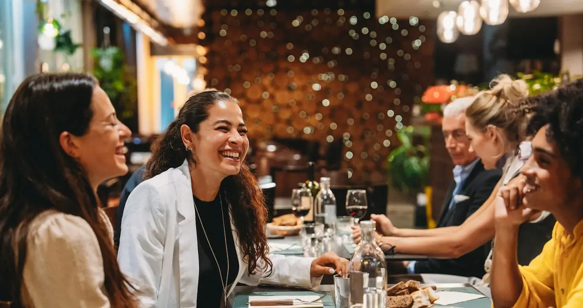 Groups of colleagues laughing together over a private meal in a restaurant.