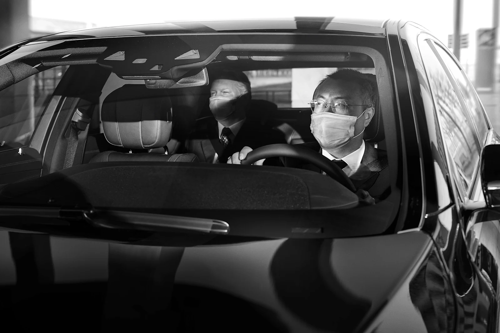 Chauffeur and guest in car with masks