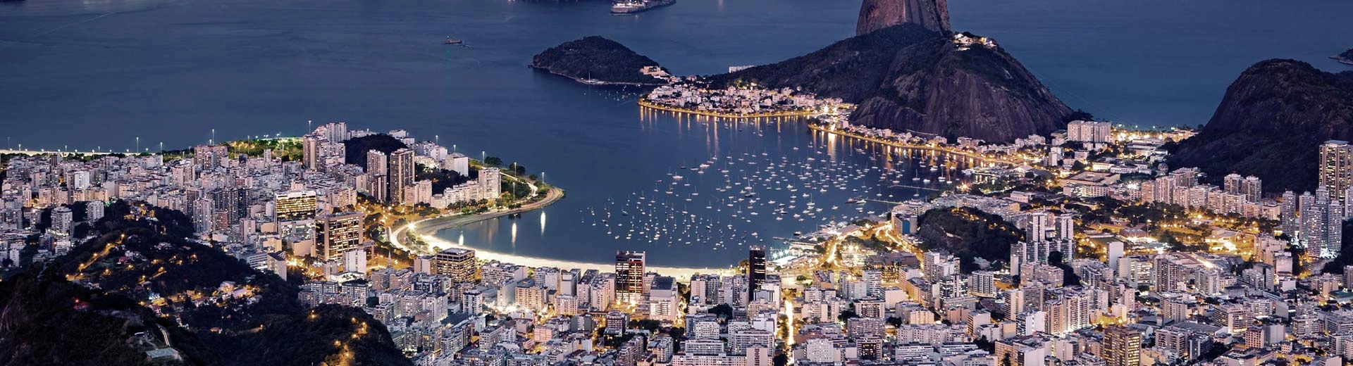 Der Strand von Rio de Janeiro ist hellweiß, selbst im Dunkeln, während die Masse der Gebäude und Menschen dahinter sträuben.