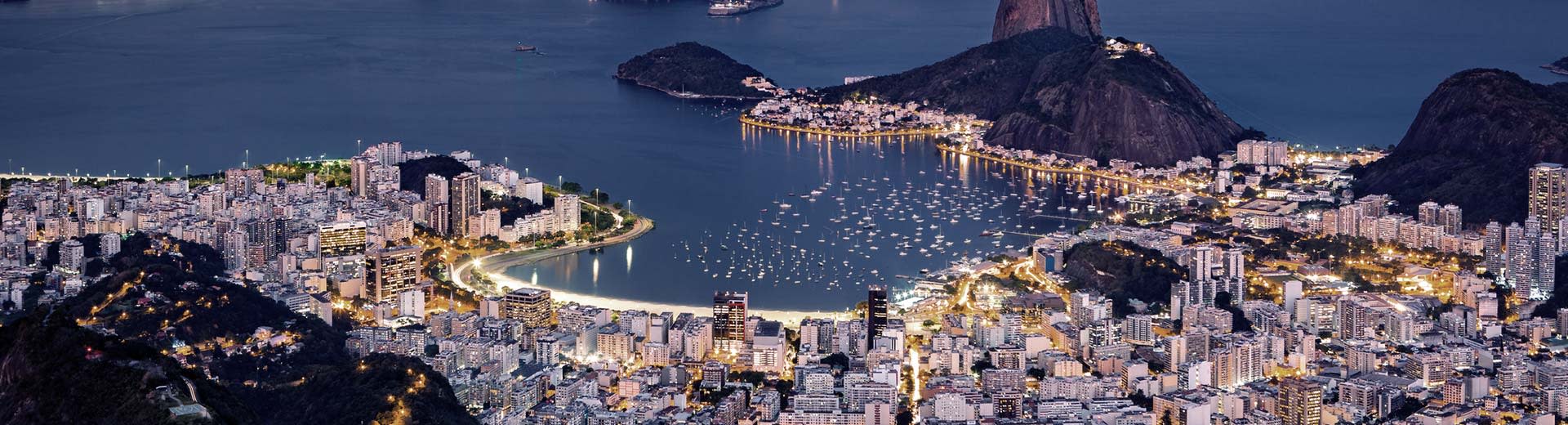 The beach of Rio de Janeiro is bright white, even in the dark, as the mass of buildings and people bristle behind it.