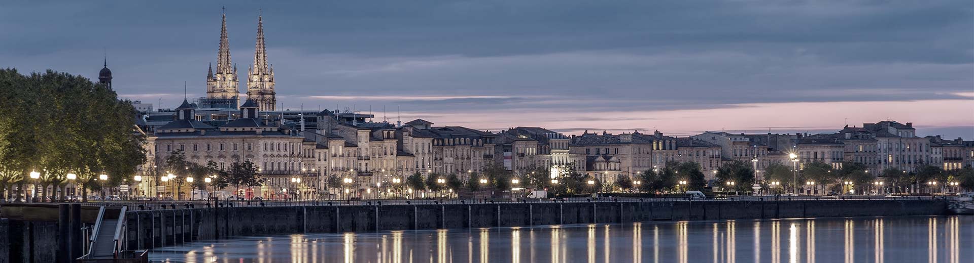 Vista del río Garrone por la noche con luces de la ciudad y edificios a la izquierda.