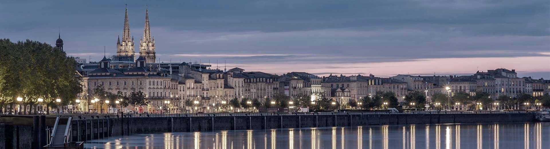 View  of the River Garrone in the evening with city lights and buildings alongside to the left.