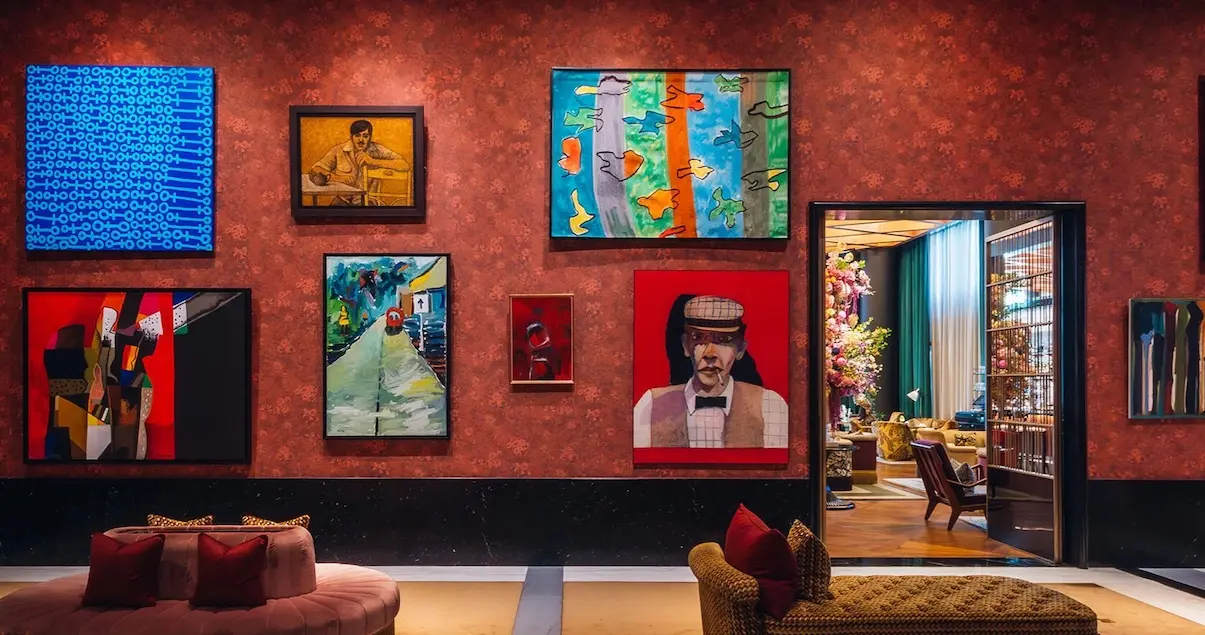 Shot of artworks on the wall of the Arts Club in Dubai, with chaise longues in the foreground and a drawing room in the background.