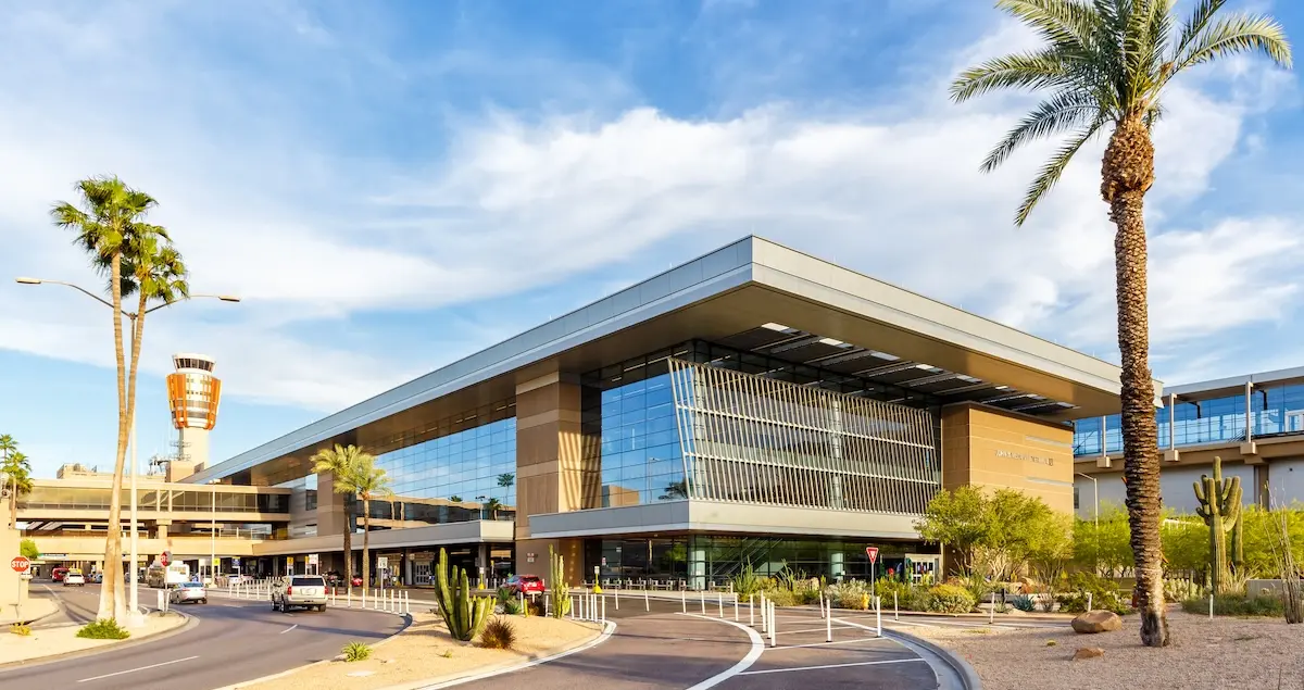 Exterior shot of the main building of Terminal 3 at Phoenix Sky Harbour Airport, with palm trees in the foreground and the control tower in the background.