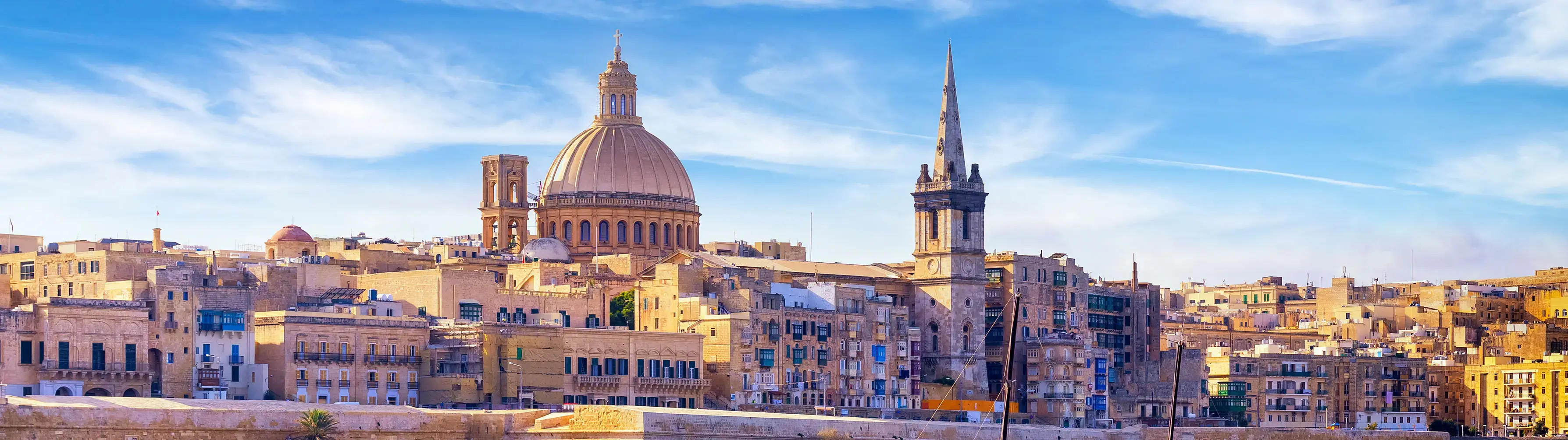 The skyline of Valletta, Malta, with a bright sunny sky behind it, shot from the docks.