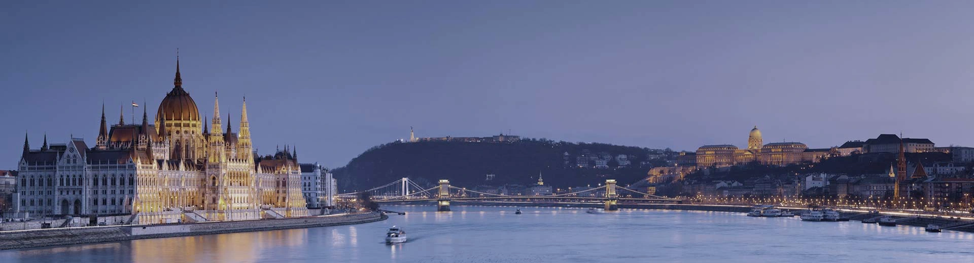 The Danube River during an sunset with a purple sky and the Hungarian House of Parliament to the left.
