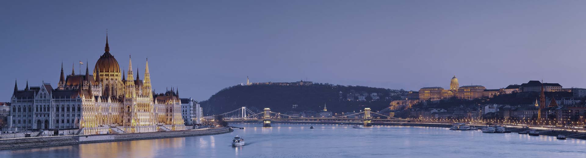 The Danube River during an sunset with a purple sky and the Hungarian House of Parliament to the left.