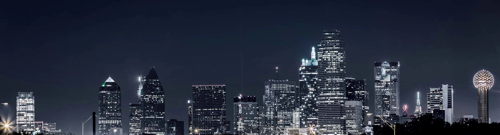 El cielo oscuro sobre Dallas está iluminado por varios rascacielos.