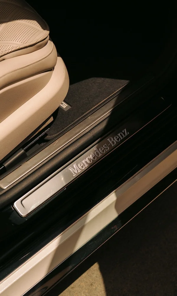Shot of the footwell detail of a Blacklane Mercedes EQS with the brand's name on brushed metal.