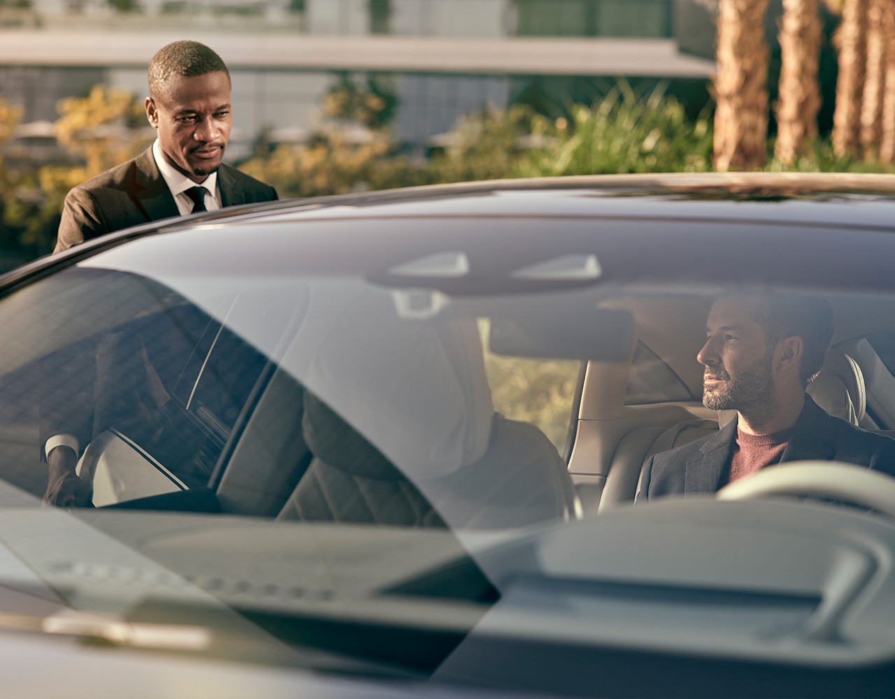 Un chauffeur ferme la porte de sa voiture alors qu'un passager est assis à l'arrière.