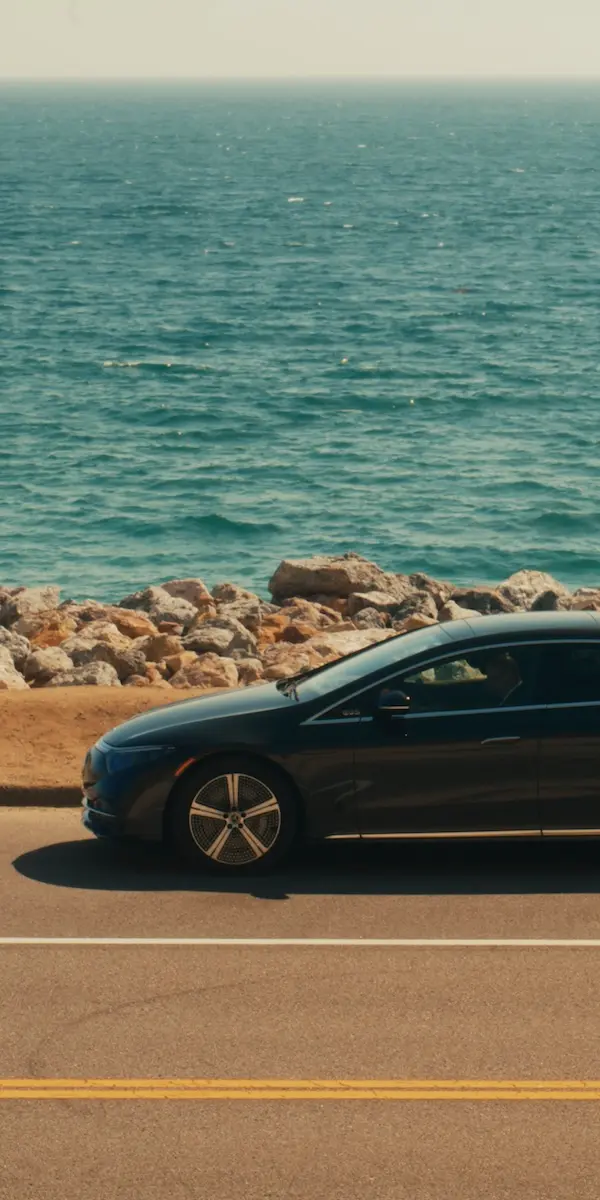 Side-profile of a Blacklane Mercedes EQE with the ocean in the background.