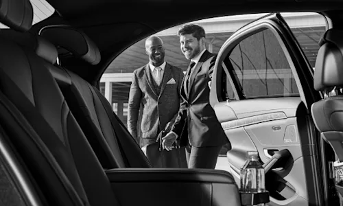 Douglas, a real Blacklane chauffeur, opens the car door for a guest.
