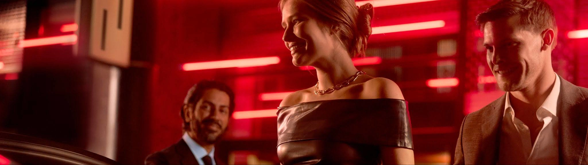 A stylish couple get into a Blacklane limousine service as their suited chauffeur holds the door open for them.