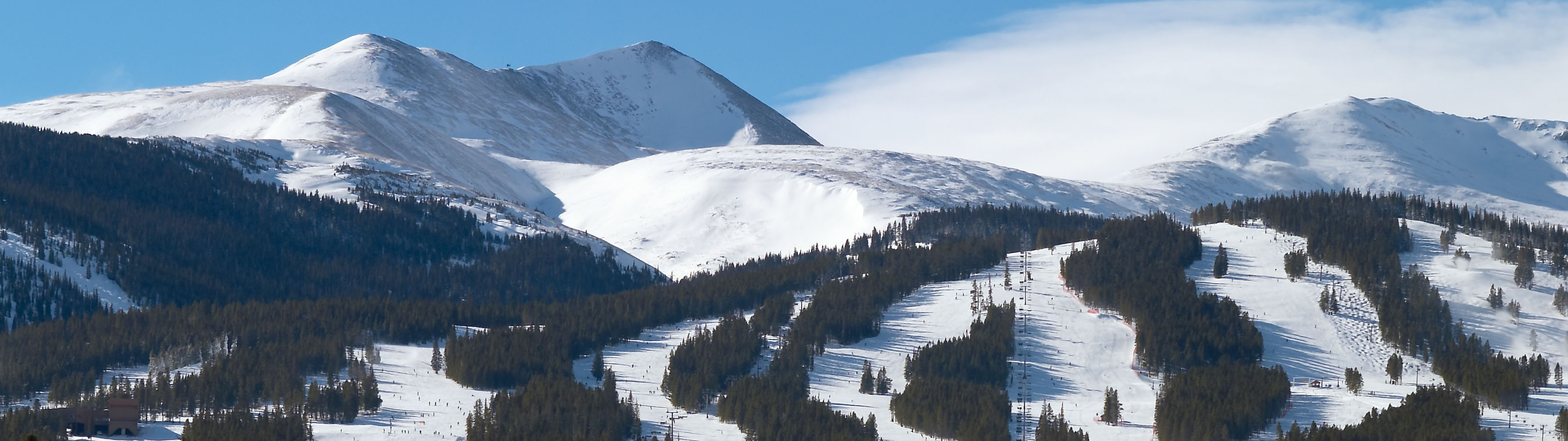 The pristene slopes of Breckenridge on a clear and crisp day. Fog covers the distant mountain peaks.