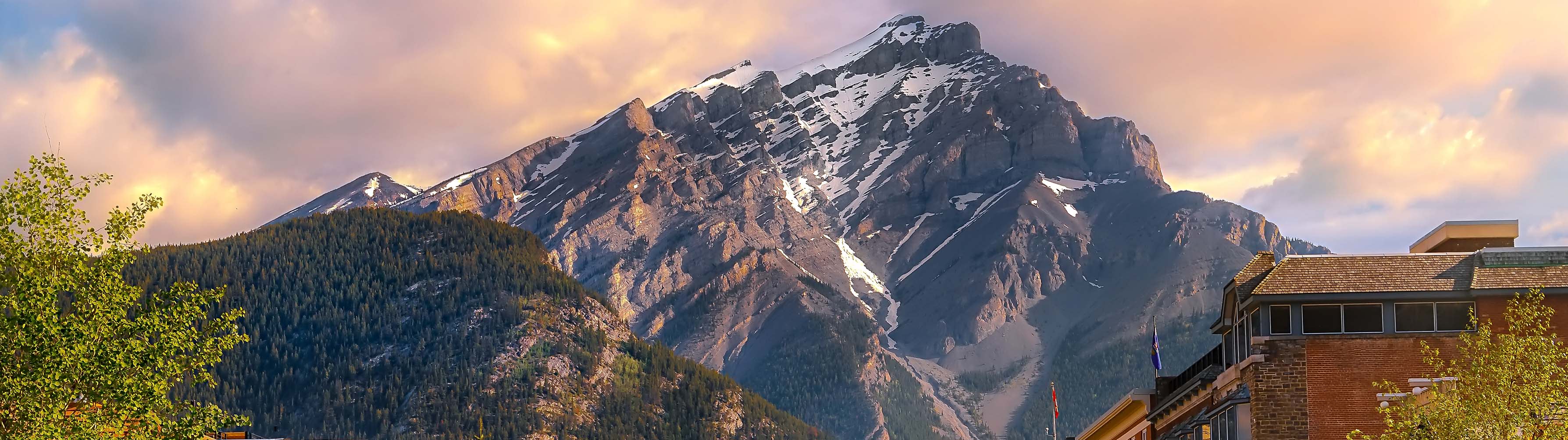 A rugged mountain peak stands against an orange sky in Banff.