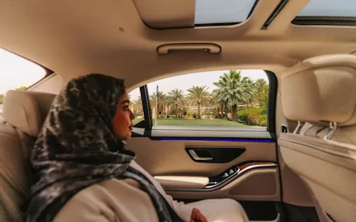 A woman in a headscarf relaxes in the back seat of a luxury Blacklane car in Riyadh.