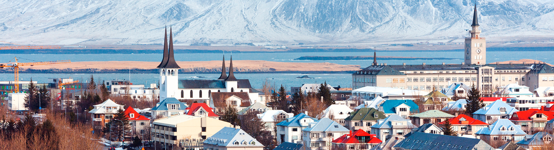 The beautiful buildings of Reykjavik lie before imposing mountains of Iceland.