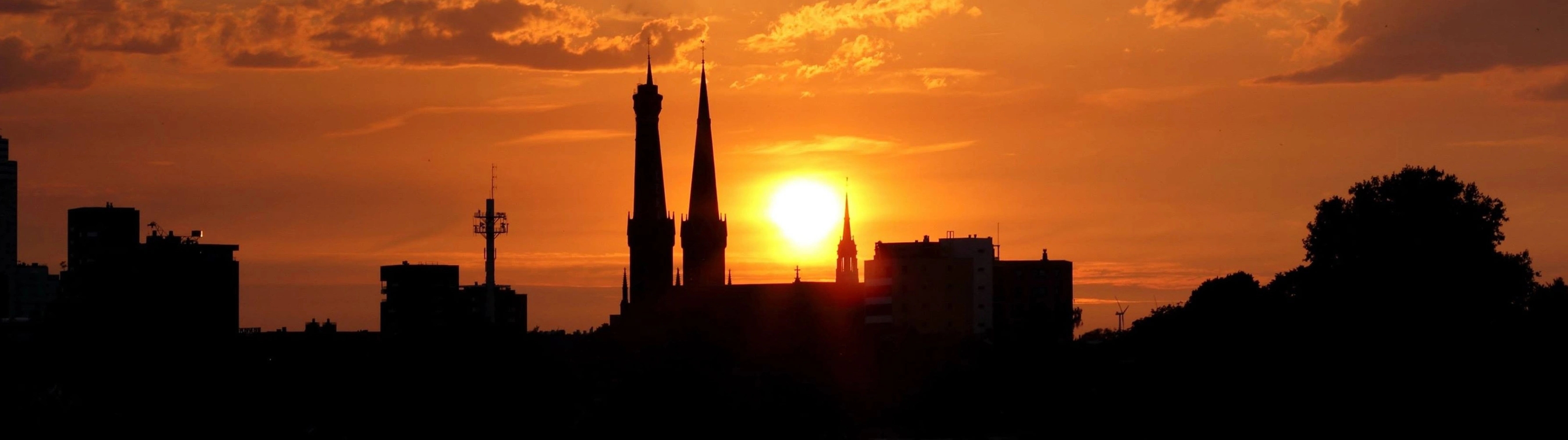 The cathedral spires of Tilburg and the city skyline at sunset.