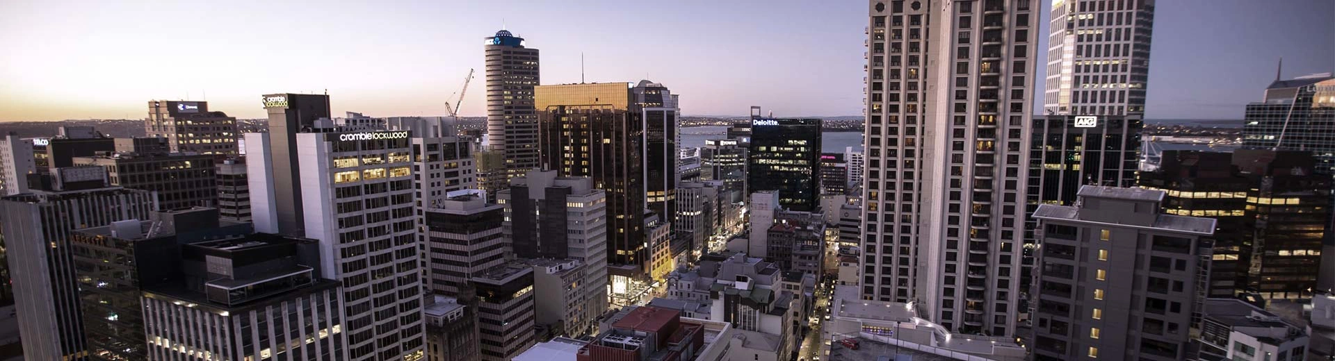 Skyline der Stadt Auckland in der Abenddämmerung mit Wolkenkratzern, die den Vordergrund dominieren.