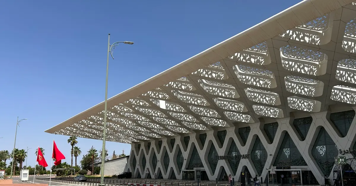 Exterior shot of the ornate terminal building at Marrakech-Menara Airport, with a blue sky in the background.