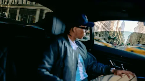 A shot of a soccer fan in the backseat of a Blacklane limo looking out the window at a Manhattan street with the Empire State Building in the background.